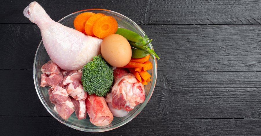 PaleoPro paleo protein powder tub surrounded by paleo-friendly foods including beef, eggs, and fresh fruit