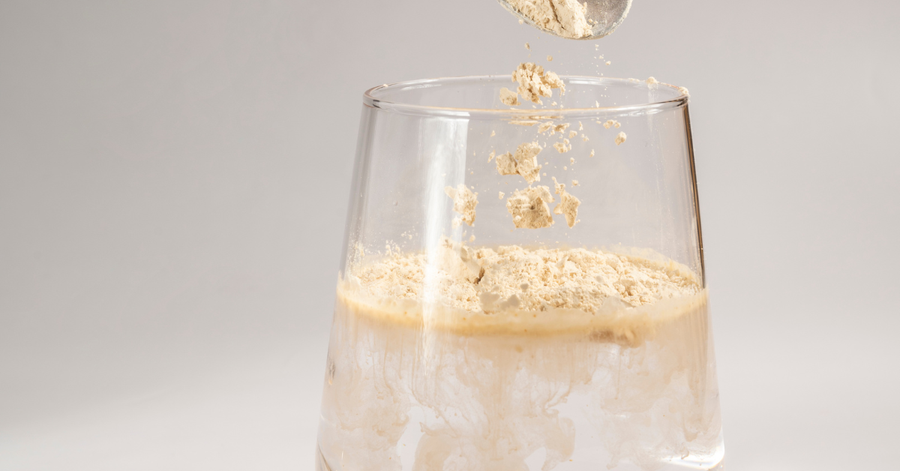 Hydrolyzed beef protein powder dissolving into water in a clear glass