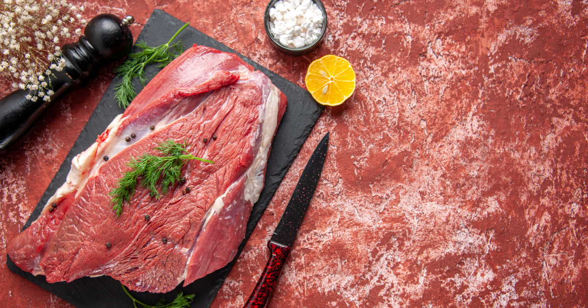Raw beef cuts including ribeye, sirloin, and ground beef arranged on a butcher board