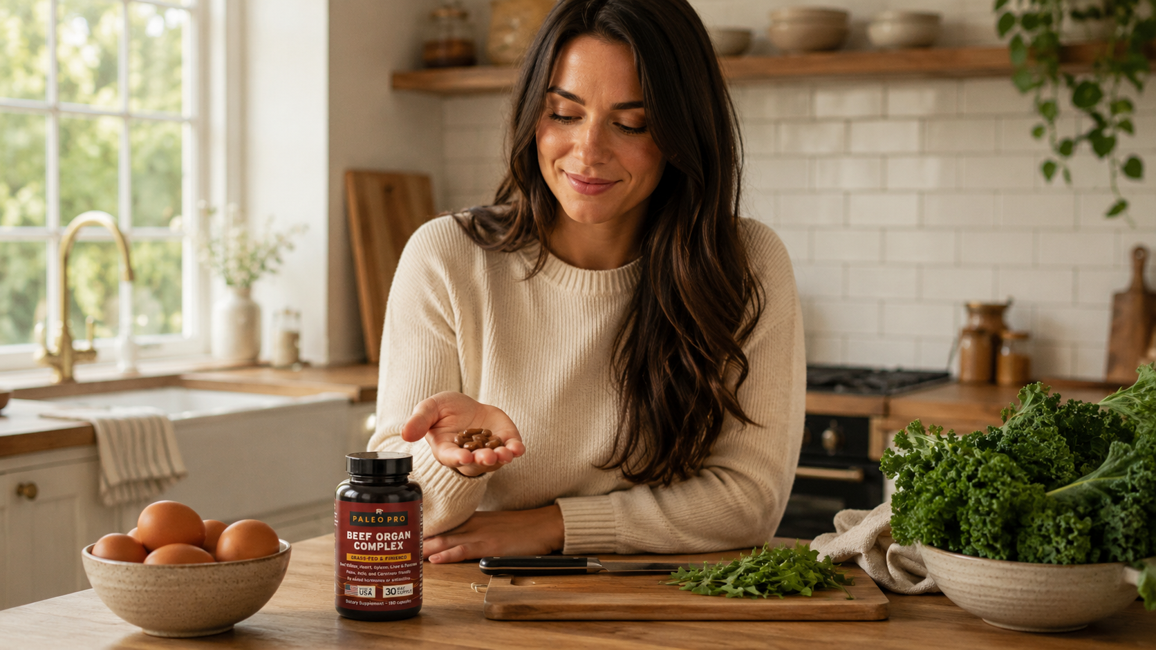 Woman in a bright kitchen holding beef organ supplement capsules beside eggs, leafy greens, and a cutting board